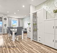 A bright interior of a 3-room apartment with a wooden decor floor and white furniture.