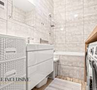 Bathroom in a 3-room apartment with a bathtub, tiles, and a floor with a wooden decor.