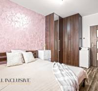 A bedroom with a bed, wardrobe, and wooden decor flooring in a three-room apartment.