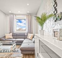 Living room with a gray sofa, glass table, and wood-patterned flooring.