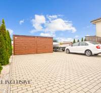 Paved parking lot with a wooden garage and a car in Gabčíkovo near a 3-room apartment.
