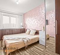 A bedroom with light walls, a wooden decor floor, and a comfortable bed in a 3-room apartment.