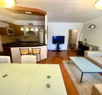 Living room in a three-room apartment with a kitchen, dining table, and comfortable seating.