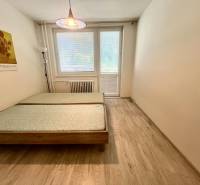 A bedroom with a light wooden bed and a painting in a 3-room apartment.