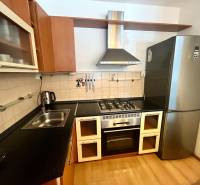 A kitchen in a 3-room apartment with a gas stove, a range hood, and a modern refrigerator.