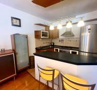 A kitchen in a 3-room apartment with a bar counter, metal chairs, and elegant lamps.