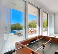 The interior of the villa with a view of the pool through glass doors, includes a foosball table.