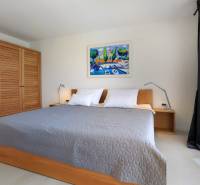 Bedroom in a villa with a large bed, wooden wardrobe, and a painting on the wall.