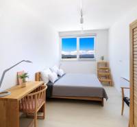 A bright bedroom in a villa with simple furniture and a view of the countryside.