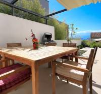 Terrace of the villa in Bale with wooden furniture, grill, and flowers, view of the countryside.