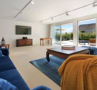 A living room in a villa with dark blue furniture, a TV, and large windows.