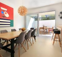 Bright dining room in the villa with a wooden table, colorful painting, and terrace.