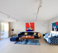 Living room in a villa with blue furniture, abstract paintings, and sliding doors to the terrace.