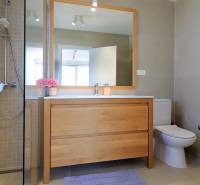 Bathroom in a villa with wooden decor, shower, and sink with a large mirror.