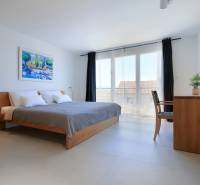 A bright bedroom with a large bed, a colorful painting, simple furniture in a villa.