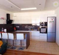 A kitchen in a 3-room apartment with a bar counter, white cabinets, and modern appliances.