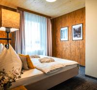 Bedroom in a 2-room apartment with wooden paneling, carpet, and two paintings on the wall.