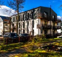 The exterior of the apartment building on Lúčná Street in Štrba with parked vehicles and a landscaped surroundings.