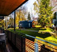 The balcony of a 2-room apartment on Lúčná in Štrba with a view of the garden with trees.