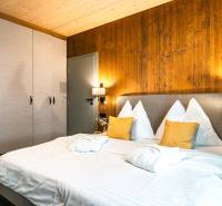 Bedroom in a 2-room apartment with a bed, wardrobe, and wall with wooden decor.