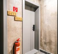 Concrete hallway with doors to a 2-room apartment and a fire extinguisher.