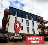 Apartment building on Lúčná Street in Štrba with a marked parking space in the foreground.