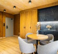 Interior of a 2-room apartment with wood-patterned flooring, wooden walls, and a black kitchen unit.