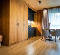 A room in a 2-room apartment with a kitchenette, wooden walls, and a floor with a wood decor.