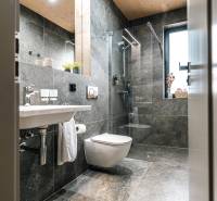 A bathroom with a shower and large gray tiles in a 2-room apartment.