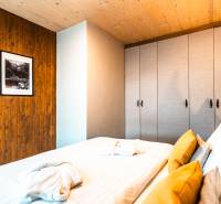 Bedroom in a 2-room apartment with a bed, wardrobe, and pictures on wooden paneling.