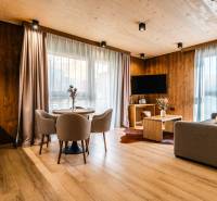 Living room in a two-room apartment with a wooden decor floor, a sofa, and a dining table.