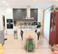 A kitchen in a 3-room apartment with a wooden decor floor, a dining table, and a bookshelf.