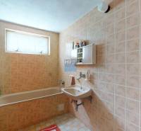 A bathroom in a family house with older tiles, a bathtub, and a sink.