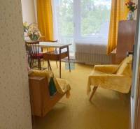 A room in a family house with a chair, table, and a yellow carpet.