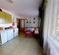 A kitchen in a family house with retro furniture, a table, a large window, and decorations.