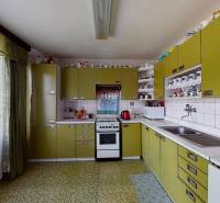 A kitchen in a family house with olive cabinets, ceramic tiles, and many cups on the shelves.