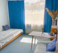 A room in a family house with blue curtains, a sofa, and a bed.