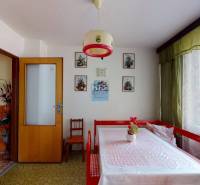 Dining room in a family house with a table, curtains, and floral paintings on the wall.
