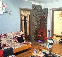 Living room in a two-room apartment with a tiled stove and a wooden decor floor.