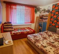 A bedroom in a two-room apartment with a wooden decor floor and colorful bed linens.