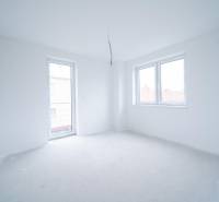 An empty room in a family house with white walls and large windows.