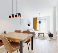 Dining and living area in a 2-room apartment with wood-patterned flooring and stylish lighting.