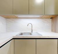 Kitchen unit with a sink, light cabinets, and backsplash in a 2-room apartment.