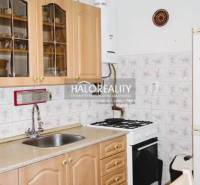 A kitchen in a 3-room apartment with wooden cabinets and a gas stove, tiled wall.