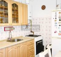 A kitchen in a 3-room apartment with wooden decor, a microwave, and a refrigerator.