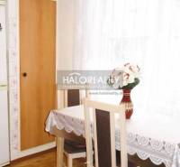 Dining room in a three-room apartment with a wood-patterned floor and light curtains.