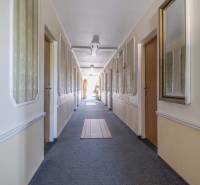 A long corridor with doors, carpets, and mirrors in a hotel or guesthouse.
