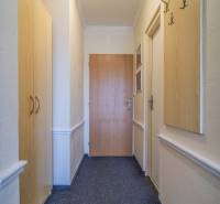 A narrow interior corridor with carpeted flooring and coat racks in hotels and guesthouses.