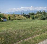 A view of a grassy area with a view of the Tatras, Poprad, hotels, and guesthouses.