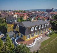 Yellow hotel with a tower, surrounded by a garden in the city of Poprad, hotels and guesthouses.